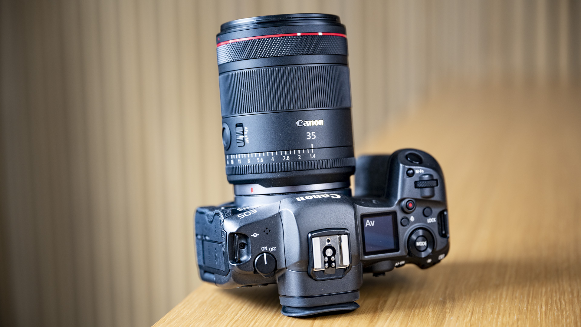 The Canon RF 35mm F1.4 lens on a wooden table, attached to a Canon EOS R5