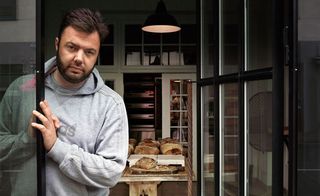 Man looking out of bakery door, with baked goods in the background