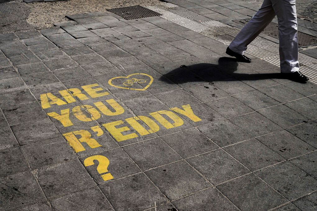 People pass by a message painted on the ground reading "Are you r'Eddy?" to mark the 50th anniversary of the first victory in a Tour of Belgian legend Eddy Merckx
