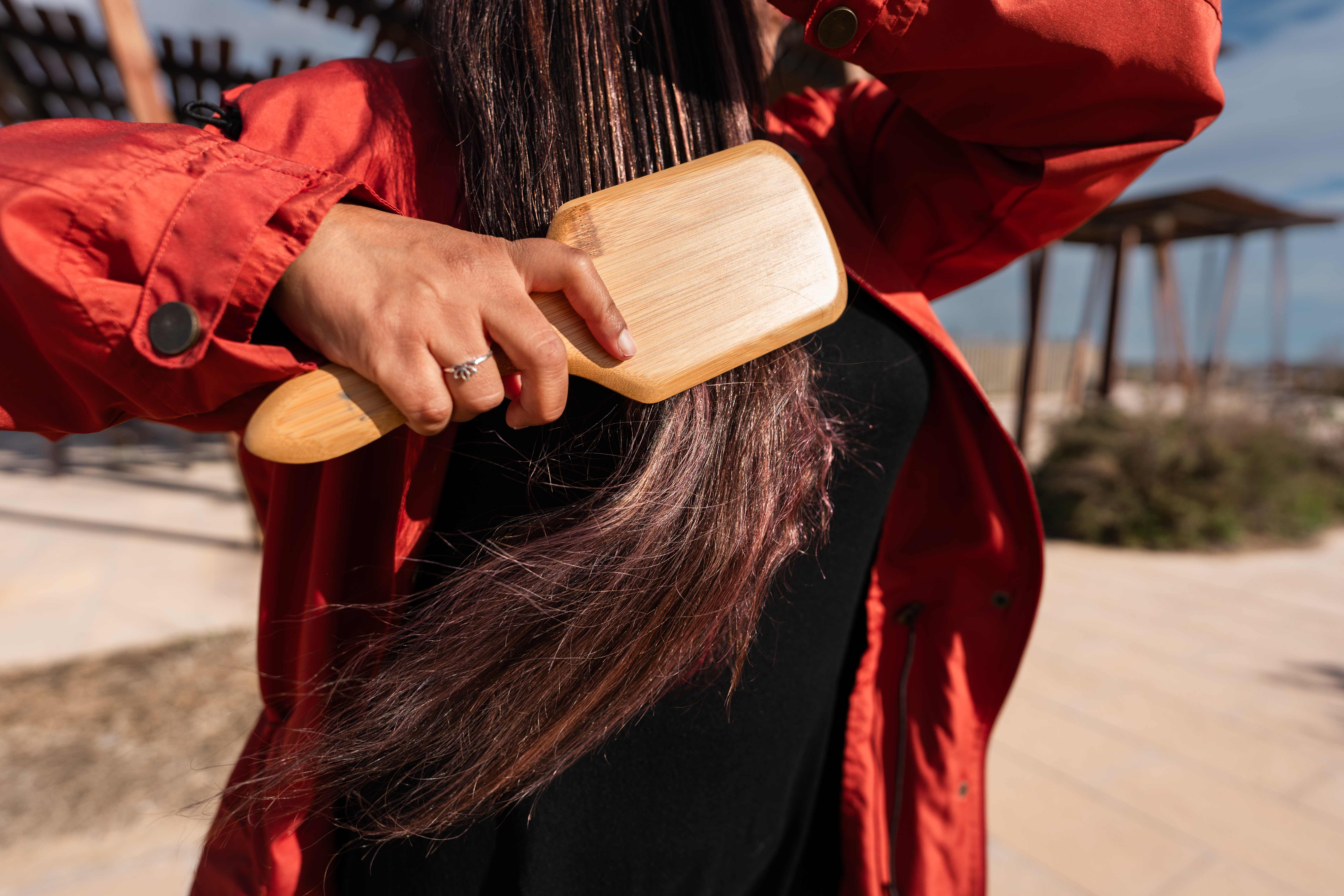 a woman in a red shirt brushing her brunette hair