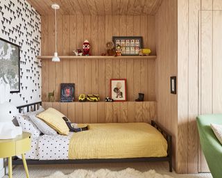 boys bedroom with yellow bedspread, shiplap, black and white wallpaper, shelving, yellow side table