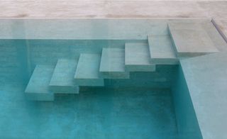 Seven concrete steps cascading down into a swimming pool