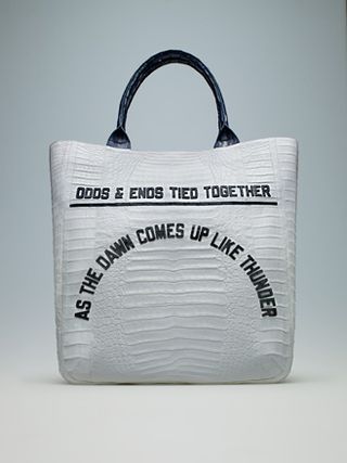 White bag with a black handle and words reading "Odds & ends tied together" at the top, with "As the dawn comes up like thunder" in an arch below