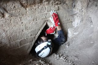 Someone from Underground Rome works their way through a narrow cavity into the underground tunnels of Hadrian's Villa