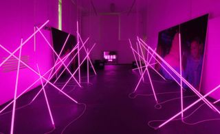 A new light installation designed by Fabio Ferrillo titled "Aisle" and created by studio OFF Arch. The rave intervention pairs large images of Italian photographer Alice Rainis' work with fuchsia fluorescent tubes.