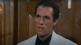 Robert Davi speaking in a wood paneled room in Licence To Kill.
