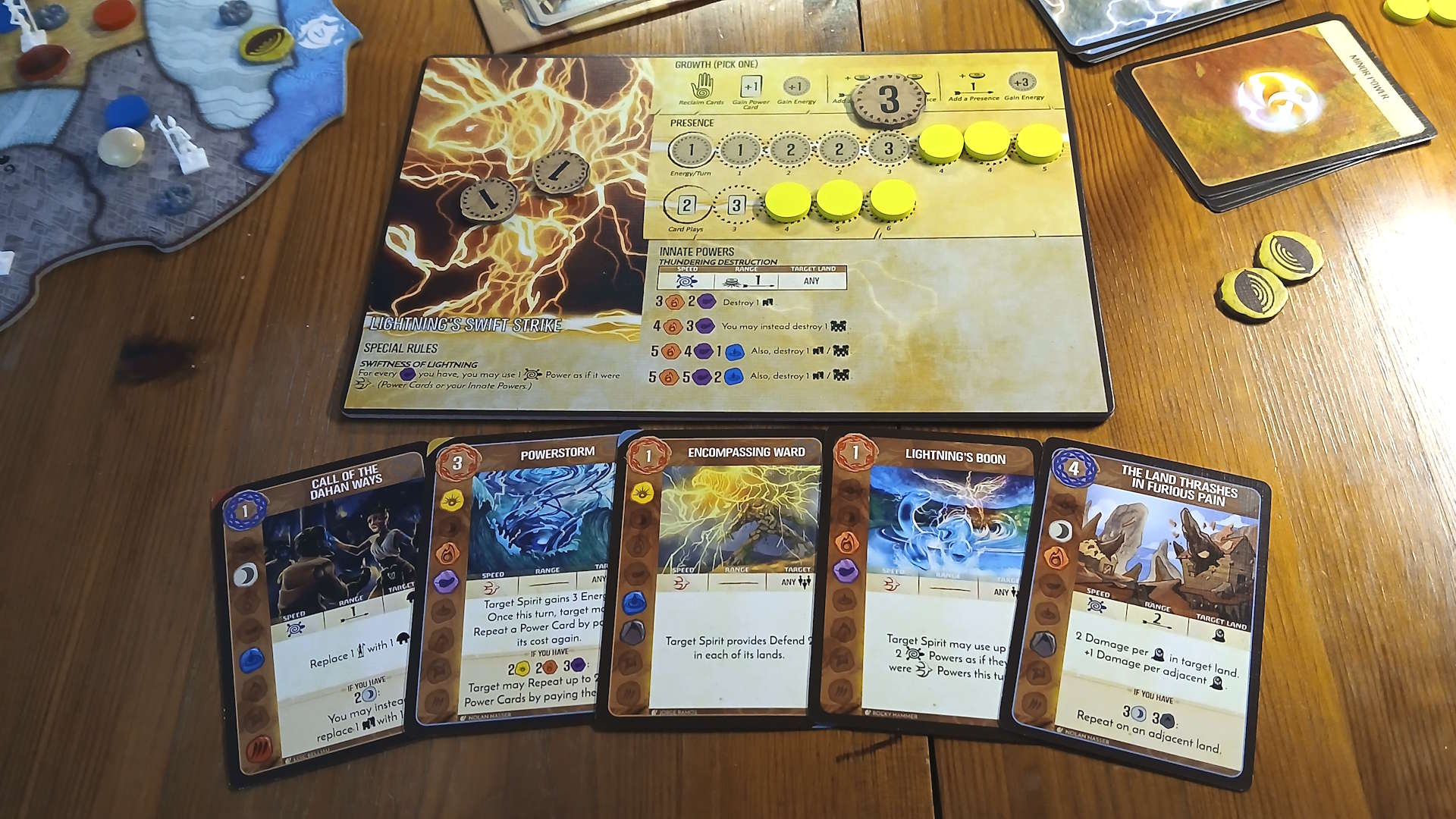 Spirit Island components, cards, and board pieces on a wooden table