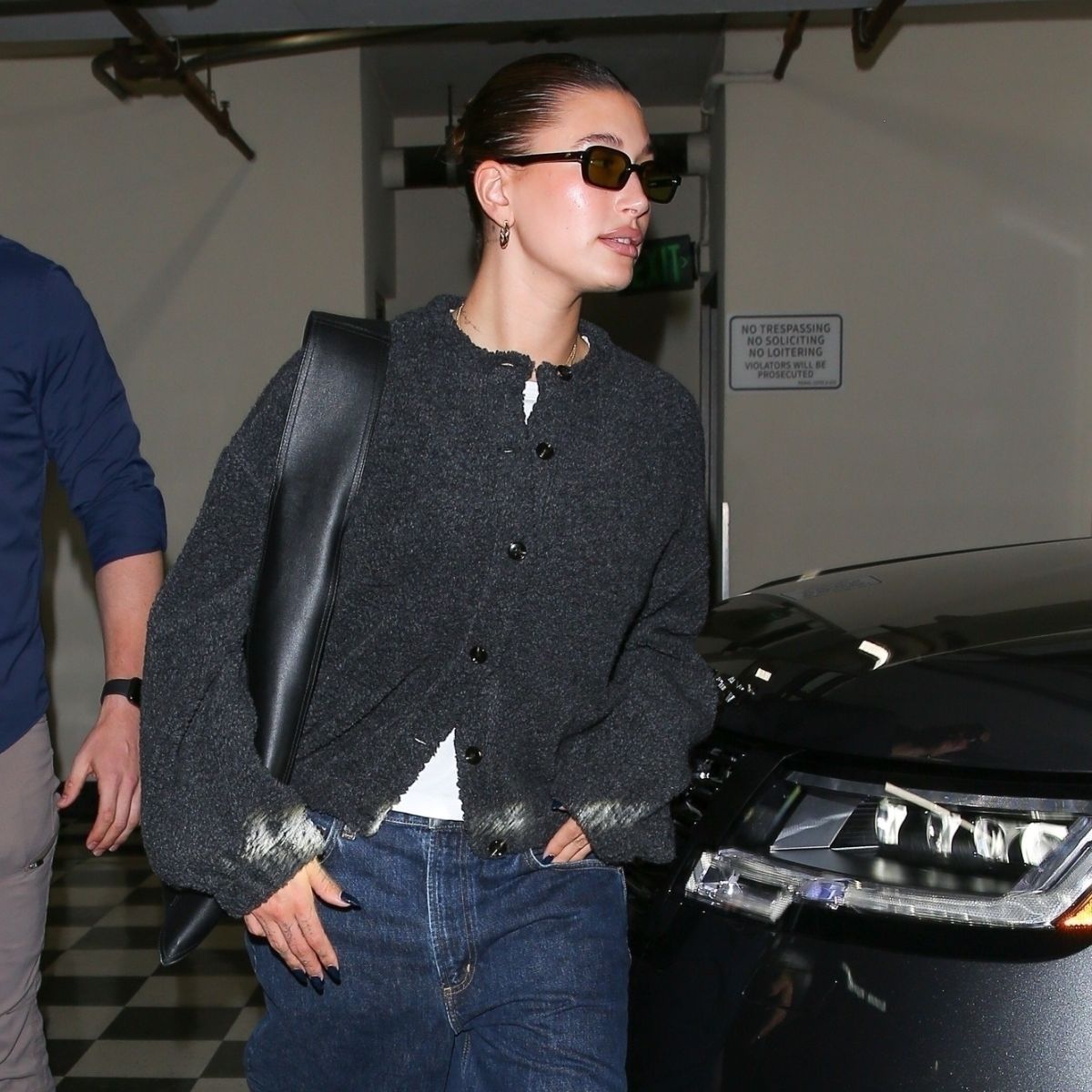 Hailey Bieber wears a grey cardigan, white T-shirt and blue jeans