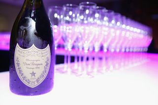 A bottle of Dom Pérignon with a row of glasses behind it