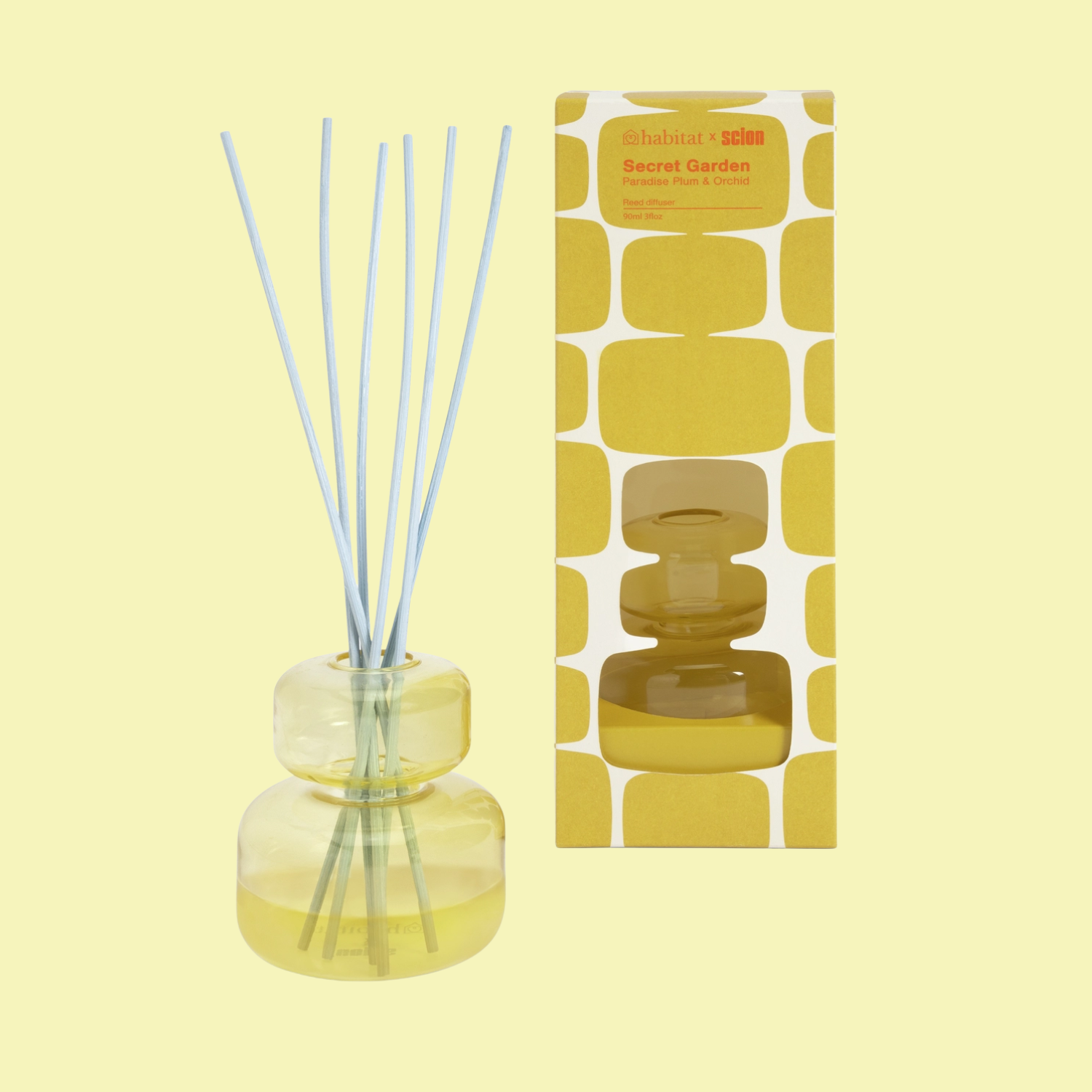 A yellow glass diffuser with light blue reeds