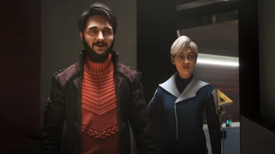 a bearded man in a red shirt stands near a gray-haired woman in a blue jacket