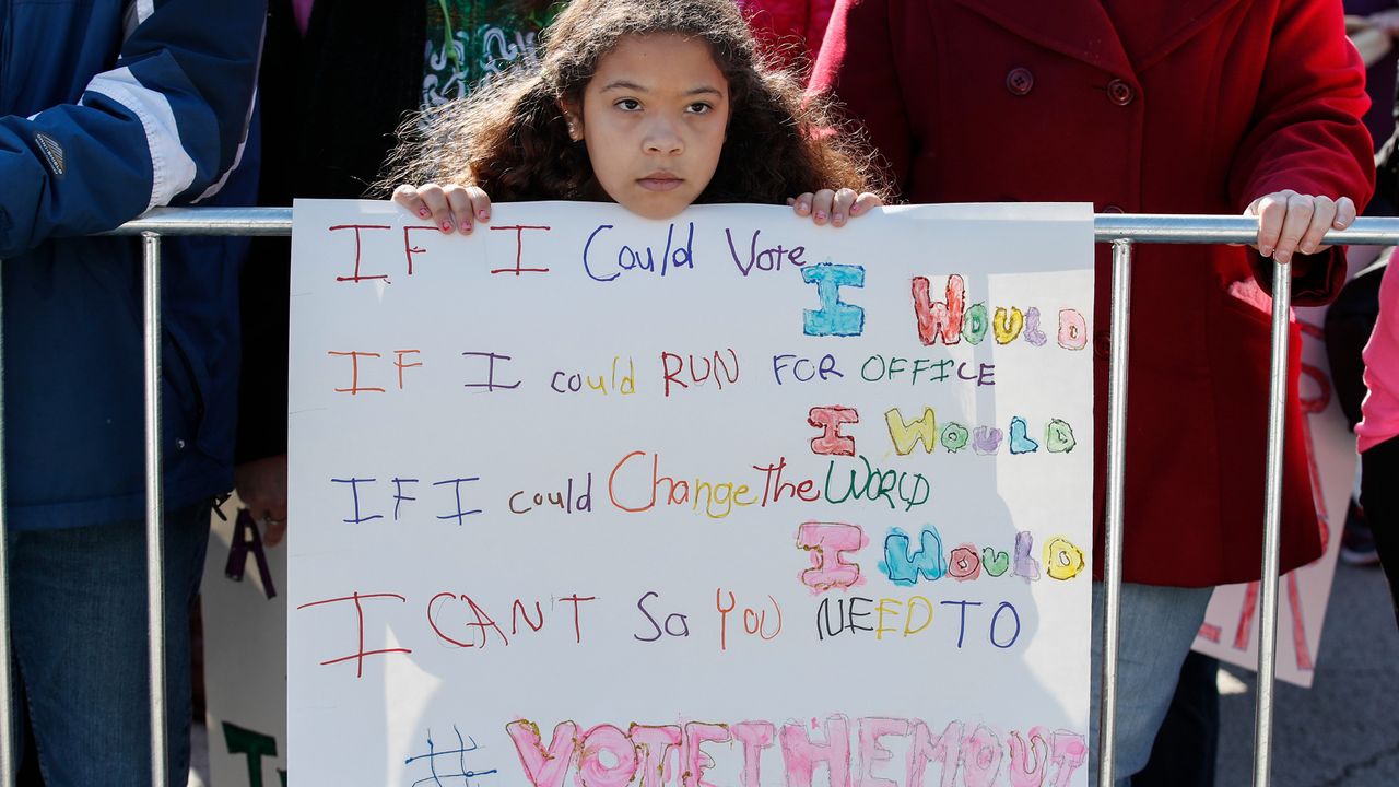 A little girl holds a sign about voting