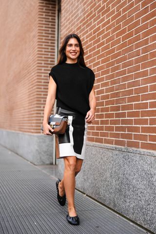 Belen Hostalet wears a black asymmetric top, a black and white leather skirt, black leather ballet shoes a brown and black leather bag, outside Fendi, during the Milan Fashion Week - Womenswear Fall/Winter 2024-2025 on February 21, 2024 in Milan, Italy.