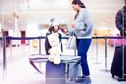 mother and daughter with luggage looking at passports in queue at the airport