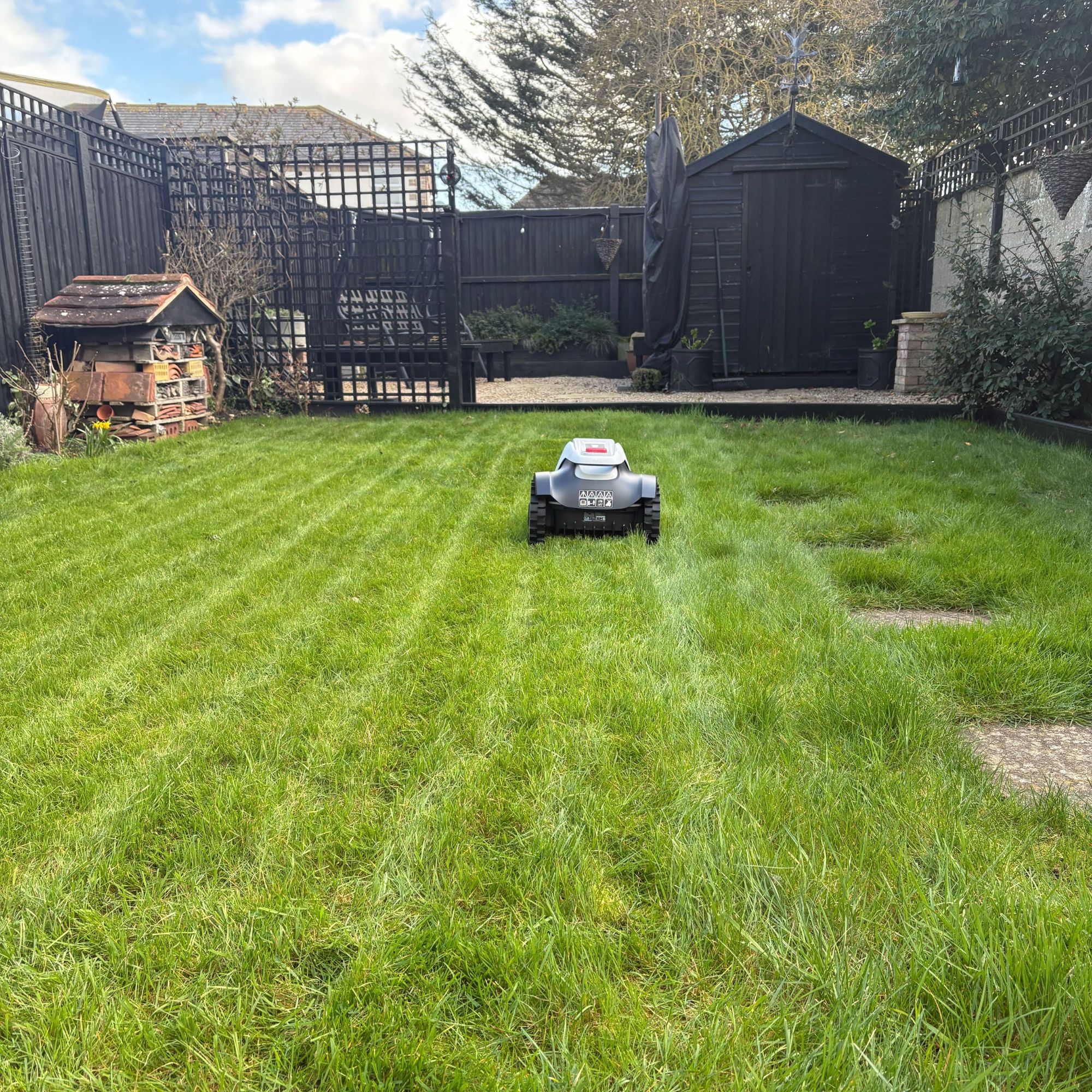 Back view of Eufy E15 Robot Lawn Mower mowing grass lawn