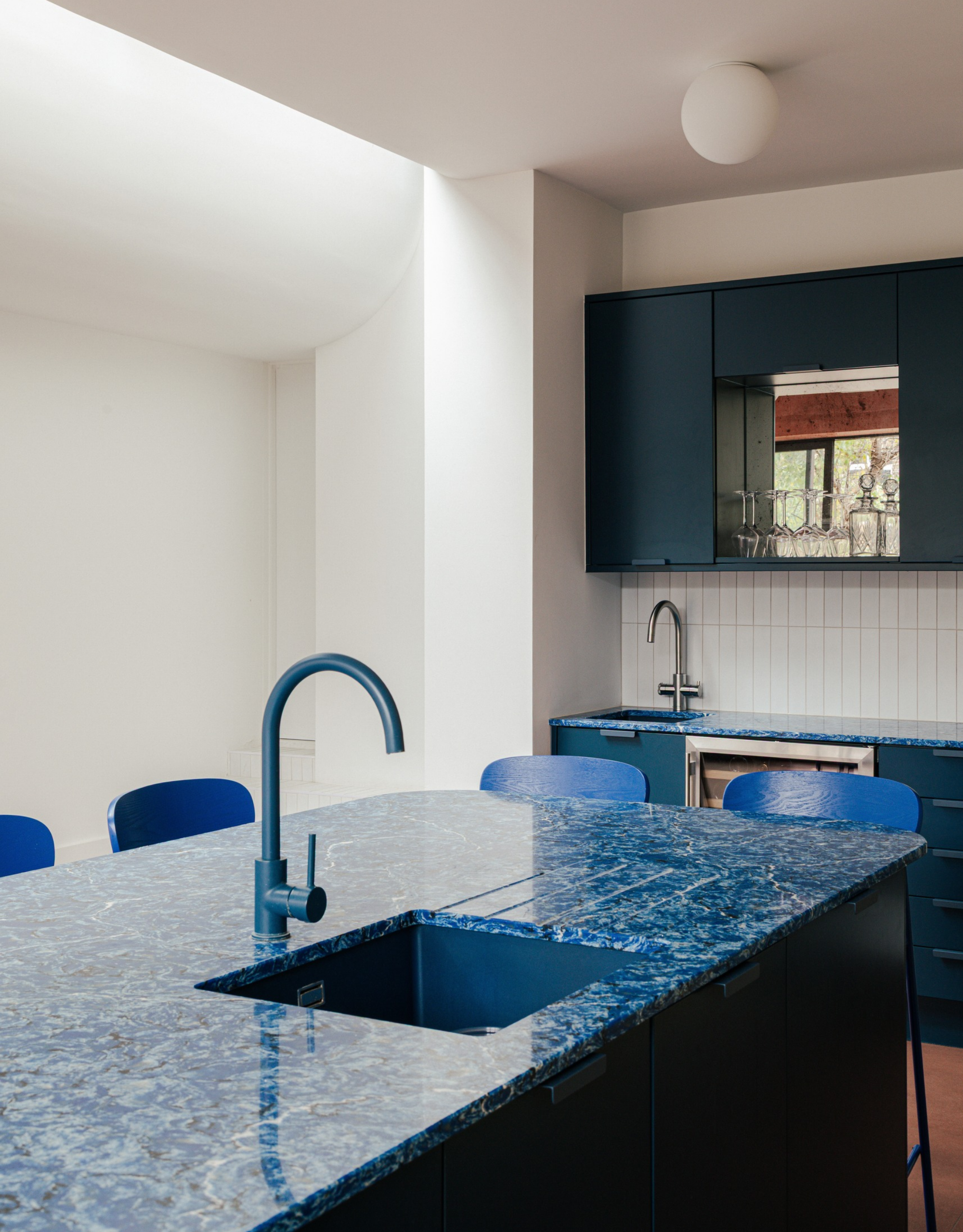 Modern kitchen with blue countertops, matching blue stools, and blue taps