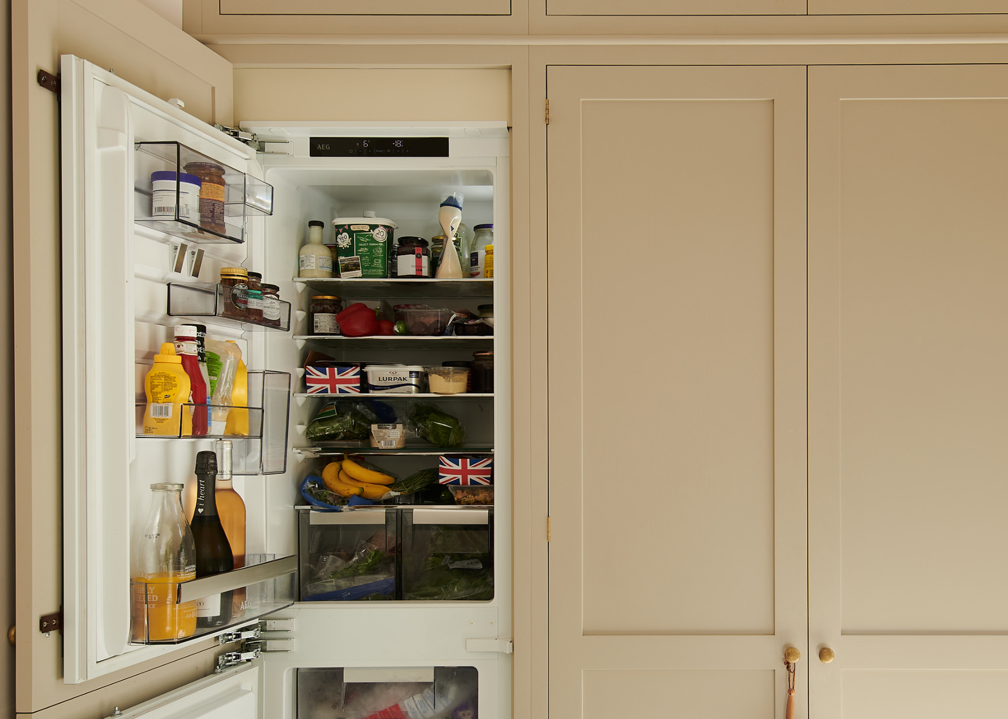 peach cabinetry with an open fridge with lots of snacks in it