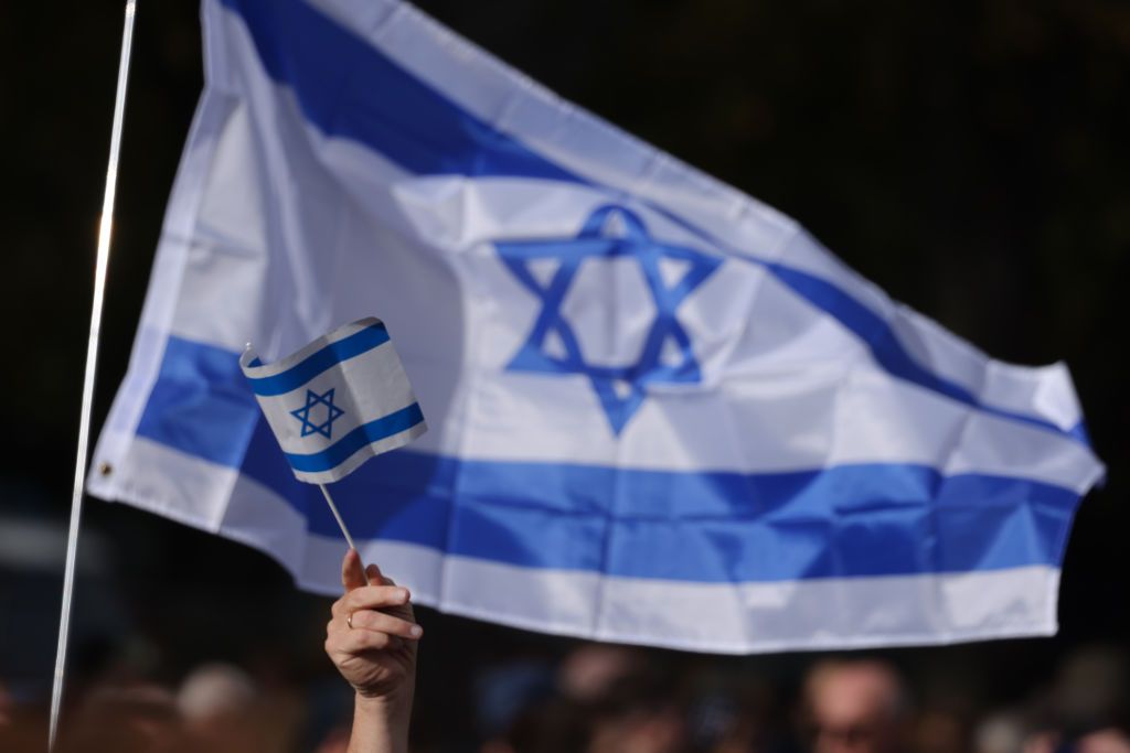 People gather under Israeli flags at a demonstration to show solidarity with Israel and against anti-semitism