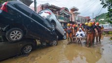 TOPSHOT - Rescuers carry a resident past cars washed away by floods at the height of Typhoon Kalmaegi at a subdivision of Cebu City in the central Philippines on November 4, 2025. At least 26 people have been killed and hundreds of thousands displaced as rains driven by Typhoon Kalmaegi flooded swathes of the central Philippines on November 4. (Photo by Alan TANGCAWAN / AFP) (Photo by ALAN TANGCAWAN/AFP via Getty Images)