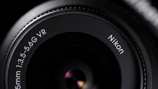 Close-up of a Nikon lens displaying specifications: 18-55mm, f/3.5-5.6G VR, highlighting its design and lens elements against a dark background