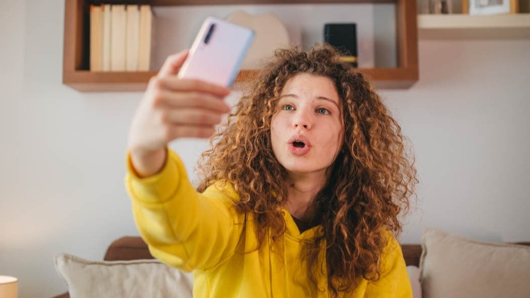A young woman on her phone, taking a selfie.
