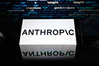 Anthropic logo is displayed on a smartphone with stock market percentages on the background
