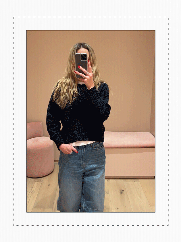 Eliza Huber in the dressing room at Me+Em's new NYC store wearing a navy blue sweater and barrel-leg jeans.