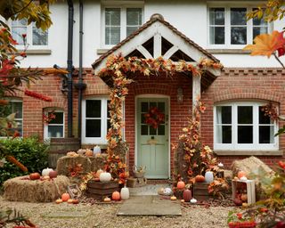Halloween door decor ideas with green door, autumnal wreath, hay, pumpkins