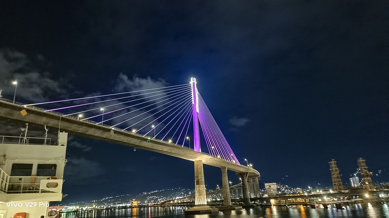 A night view of a bridge illuminated by a purple light, creating a captivating and enchanting atmosphere