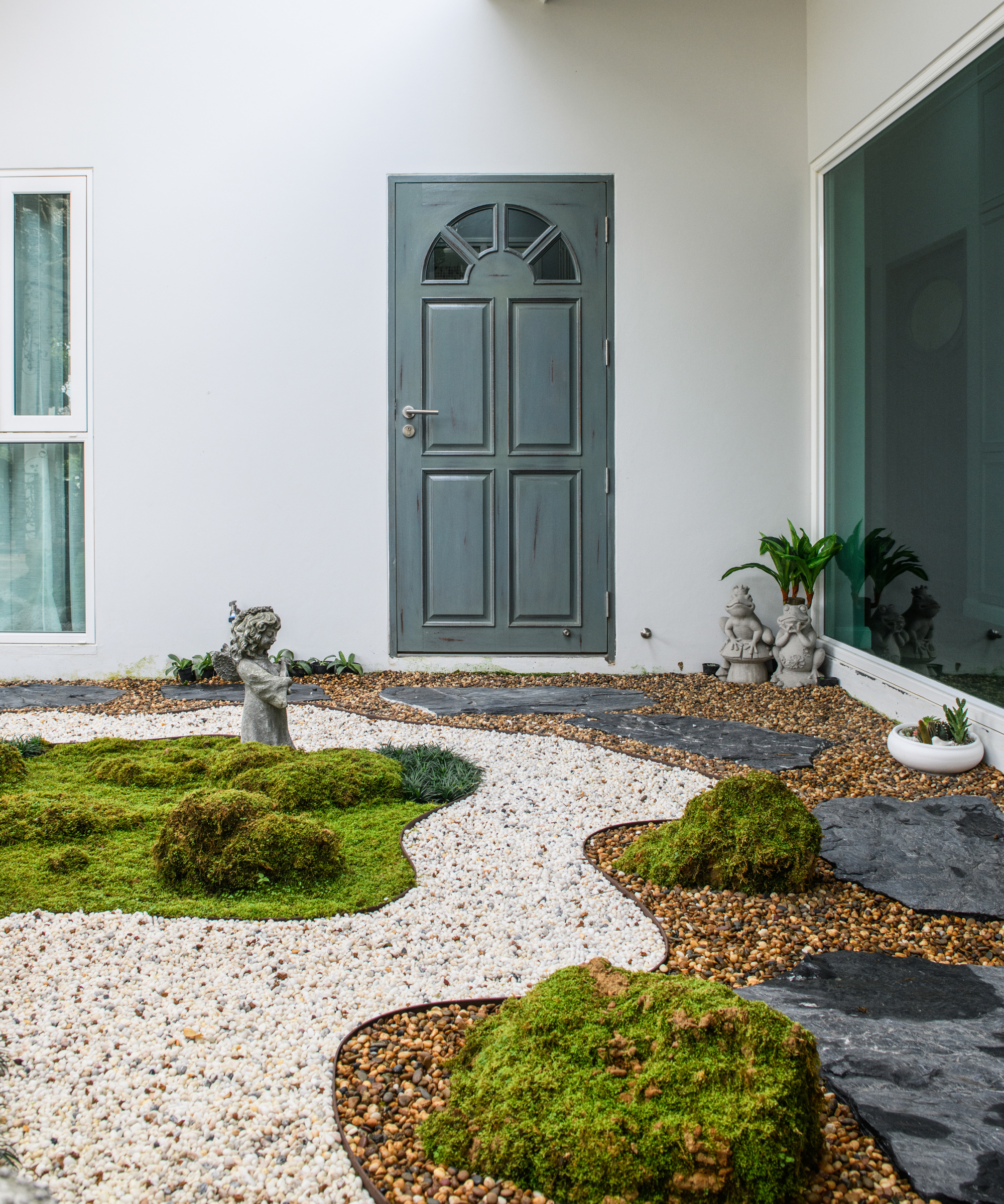 winding light gravel path to ble front door with darker gravel sections to side and black slate slabs