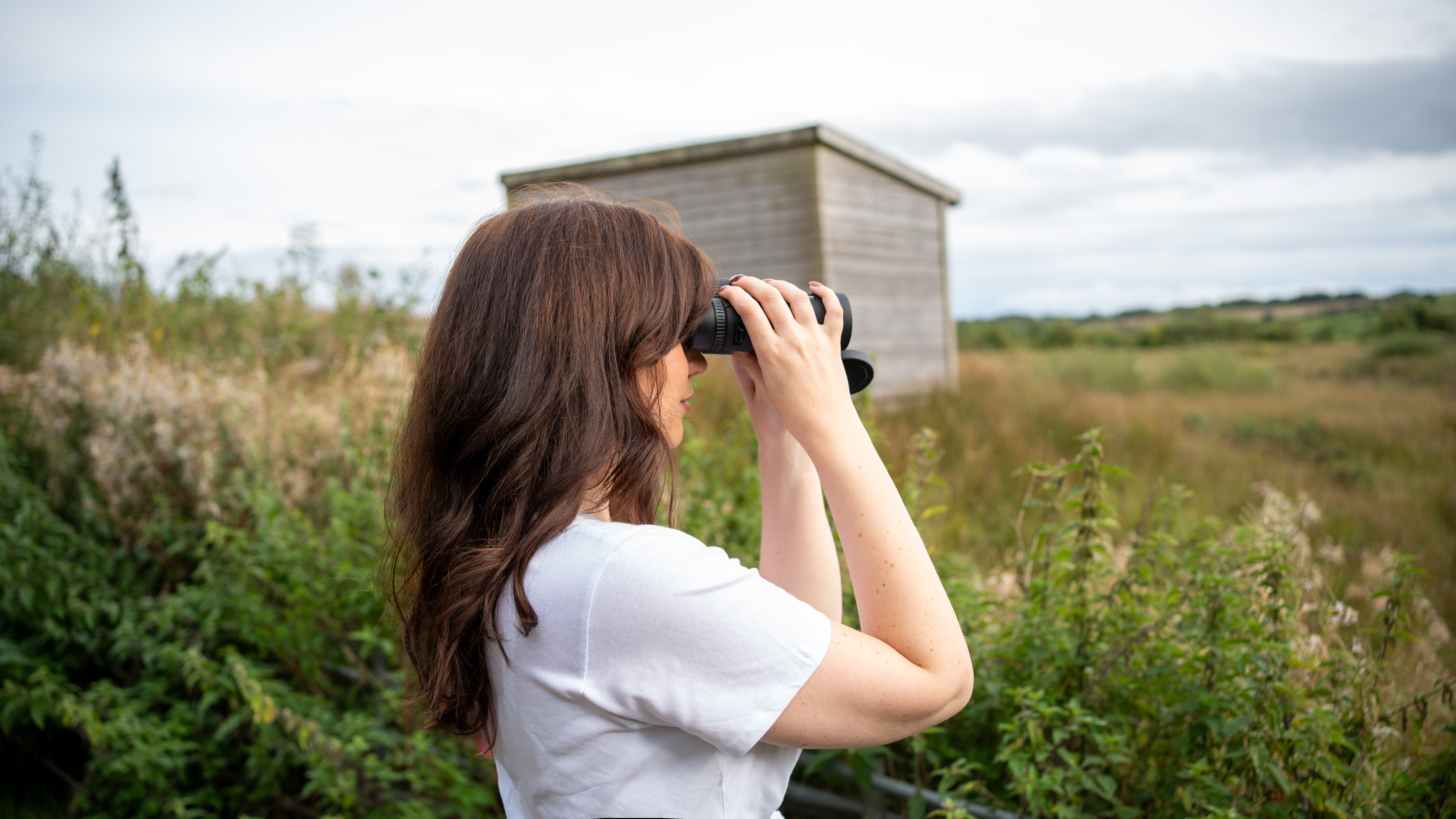 woman using the Celestron Nature DX ED 10x42 in a nature reserve