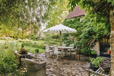 Shaded seating with a pretty Indian parasol and stone dog found in a junk shop — Harriet Anstruther's garden in West Sussex. ©Eva Nemeth