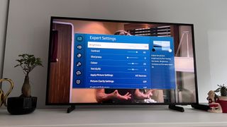 The Samsung The Frame TV 2021 pictured on a cabinet with the smart interface on the screen