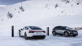 Two Audi EVs plugged in at a snowy charging station