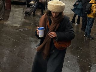 Fashion influencer @_santinaharrison wears a chic and practical look with a shearling hat and long coat that's on-trend for 2025.