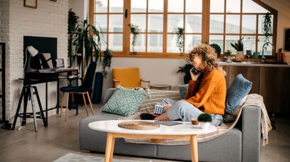 Shot of an attractive young woman using her cellphone while relaxing at home on the weekend