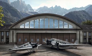 Two Rimowa aircrafts standing in front of a hangar with mountains behind them.