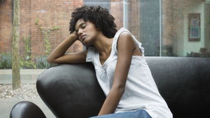 Woman falling asleep while sitting on a couch