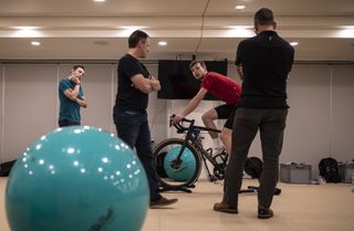 A cyclist sits on a bike while three people assess his bike fit