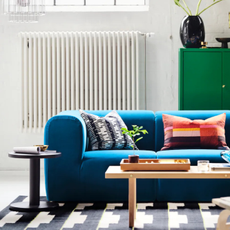 IKEA blue modular sofa on a geormetric rug with wooden coffee table.