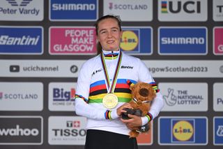 Antonia Niedermaier in a rainbow jersey holding a Highland coo soft toy