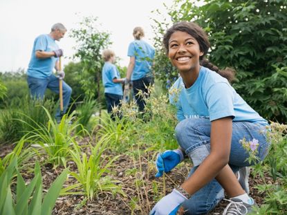 A smiling teenage girl works in a garden