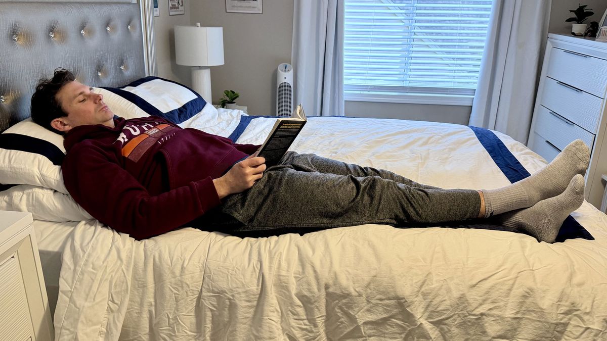 A man lying on the Winkbed mattress reading a book