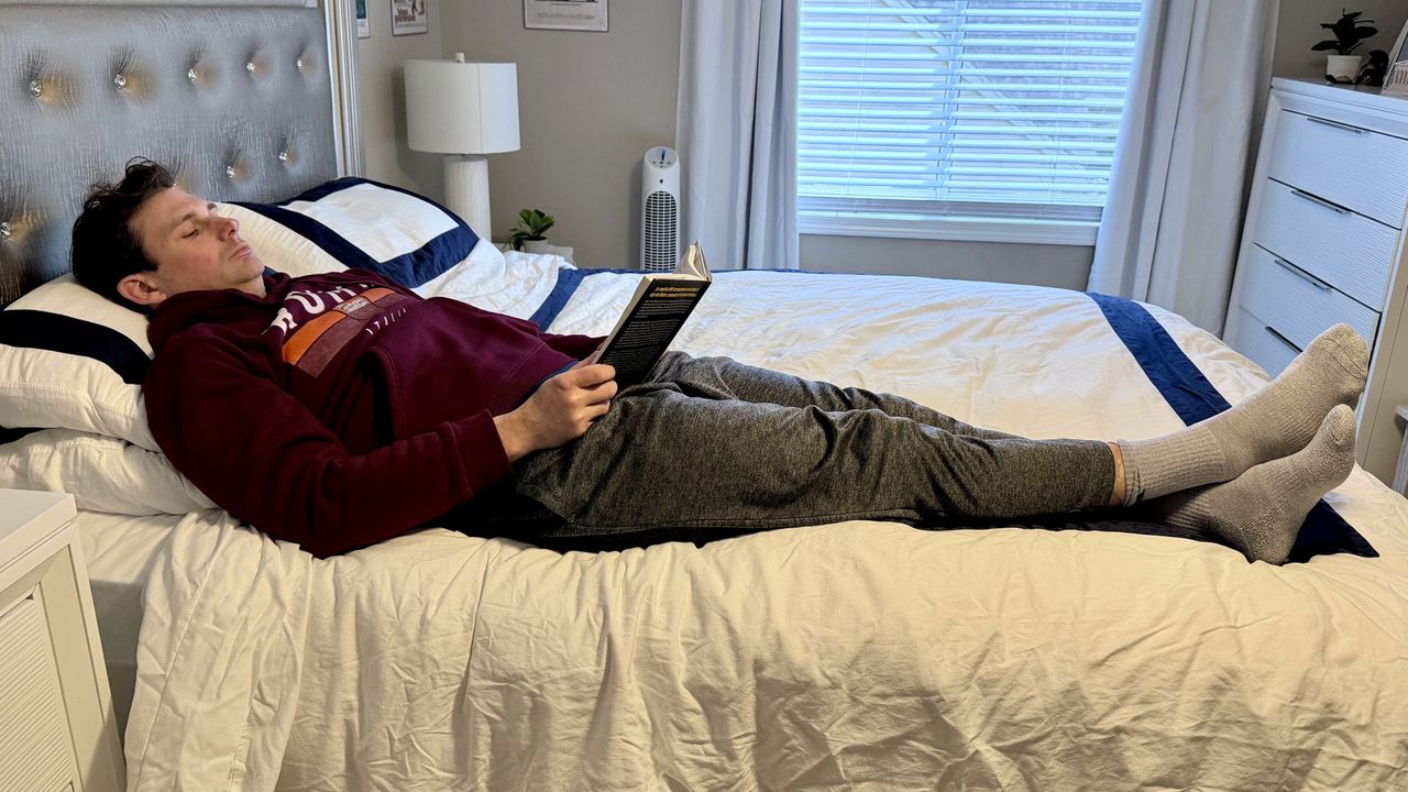 A man lying on the Winkbed mattress reading a book