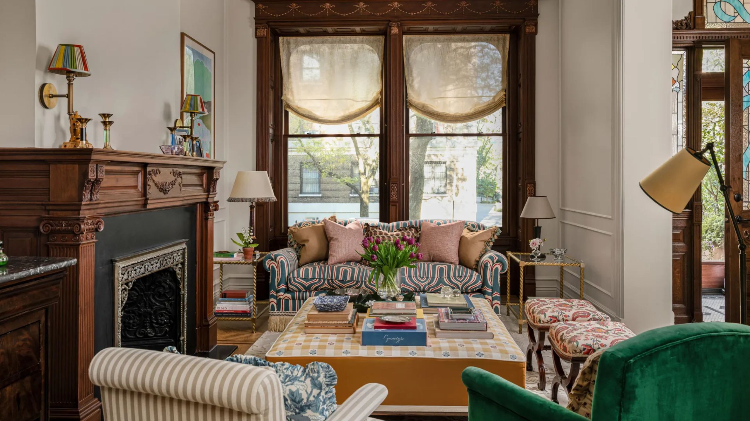 a neutral brownstone living room with original mahogany casement windows and fireplace and a layered british-style interior design