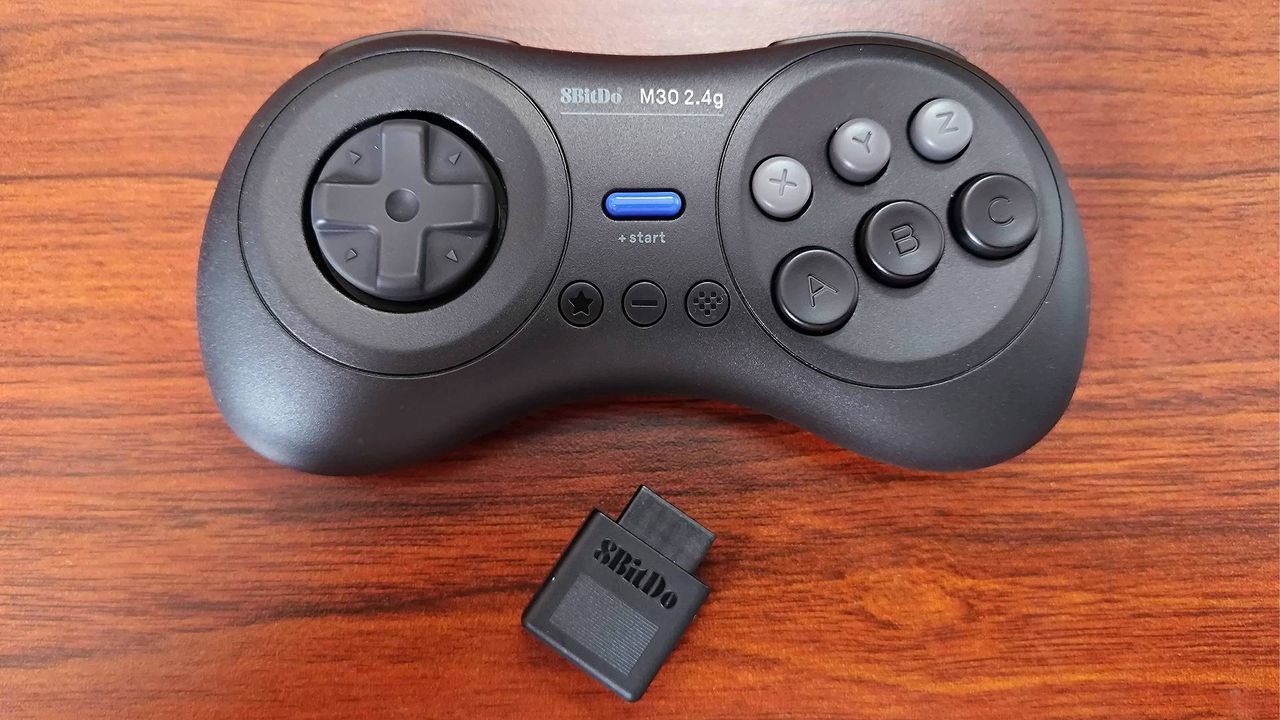 8Bitdo M30 Sega Mega Drive/Genesis 2.4Ghz Wireless controller on woodgrain desk with adapter sitting under gamepad.