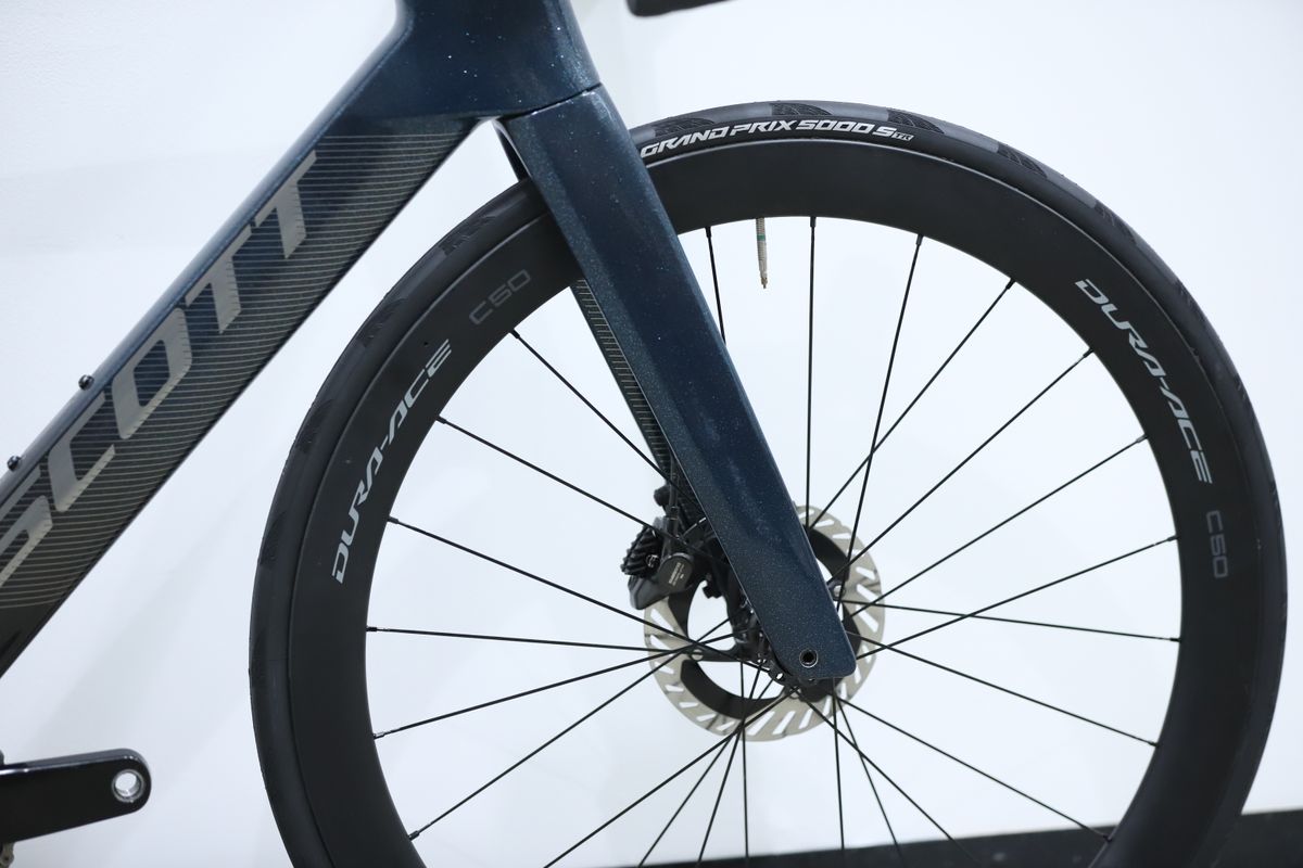 A blue Scott Foil RC Pro stands against a white wall