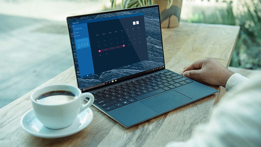 A man learns how to install apps on a laptop, with a Windows laptop on a table beside a cup of coffee