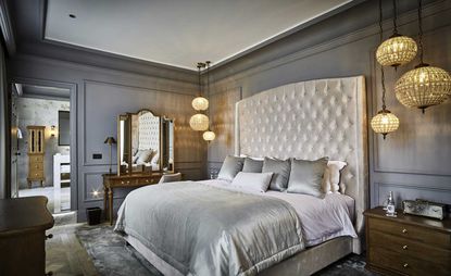 Bedroom in soft grey tones with a wooden floor, wooden dressing table and hanging lights