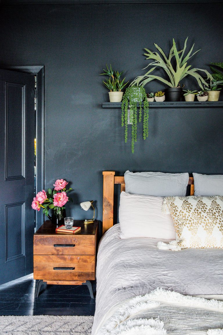 dark grey bedroom with wooden side table and hanging plants